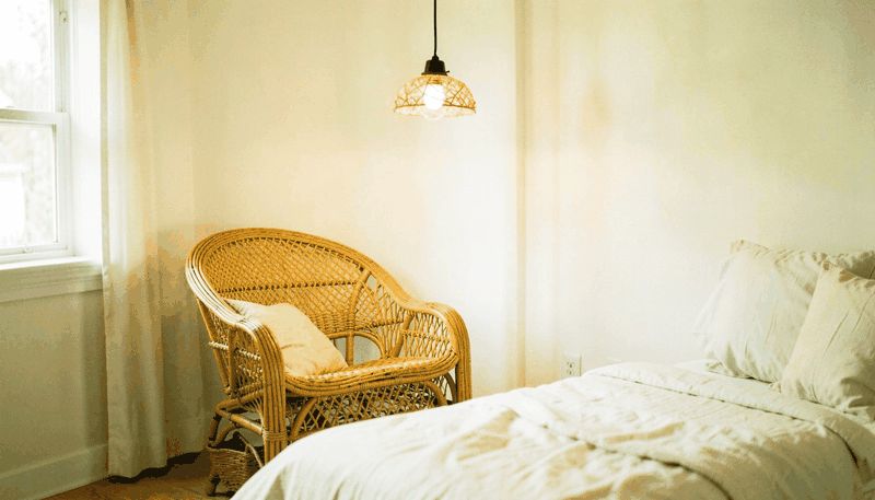 A spacious master bedroom with an upholstered bed, layered cream and taupe bedding, a reading nook by the window, and soft natural light.